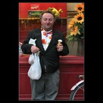 Muž se zmrzlinou, klíči a taškami, na pozadí květy <i>a prý kolo</i>