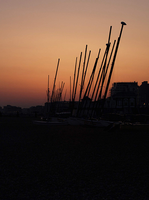 Brighton beach blizko West End Pier, UK. Plachetnice po zapade slnka.