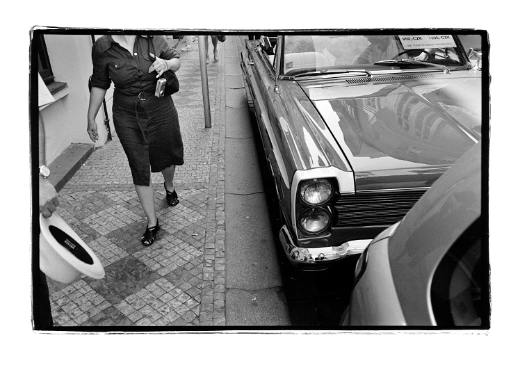 Klobouk, náramkové hodinky, fotoaparát, sandály na výletě a automobil