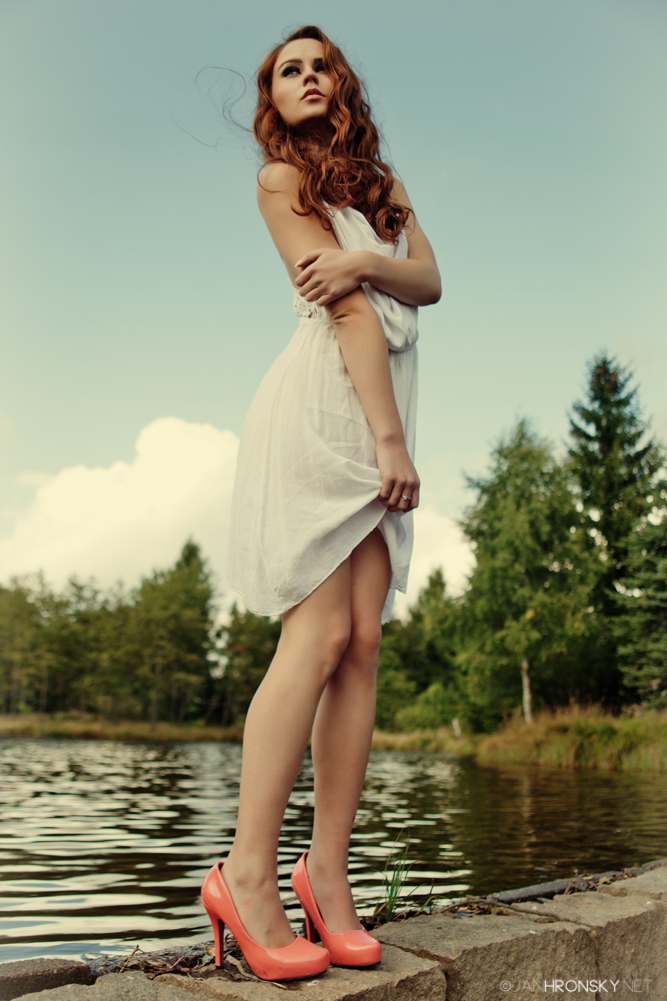 Manekýna v lososových lodičkách a bielych šatoch na kraji rybníka