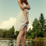 Manekýna v lososových lodičkách a bielych šatoch na kraji rybníka