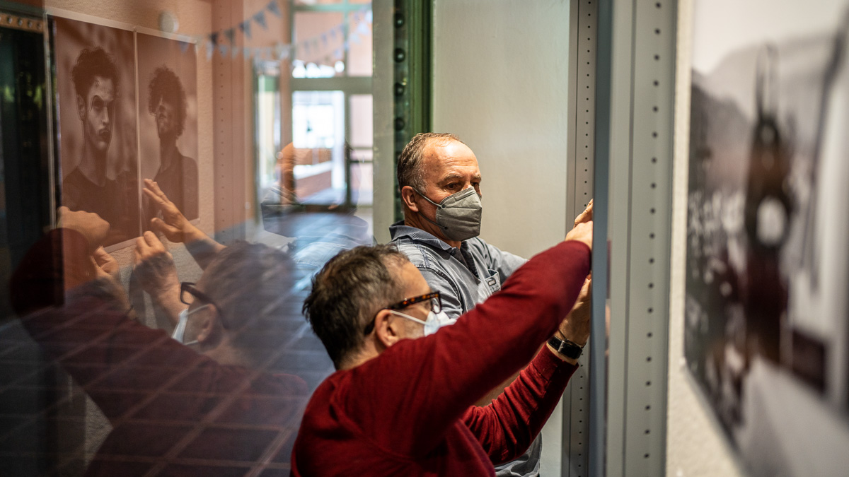 Umelec instaluje umelecke dilo jineho umelce spolecne s kuratorem vystavy