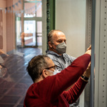 Umelec instaluje umelecke dilo jineho umelce spolecne s kuratorem vystavy