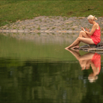 U jezírka žena sedí, jako každý v mobil hledí